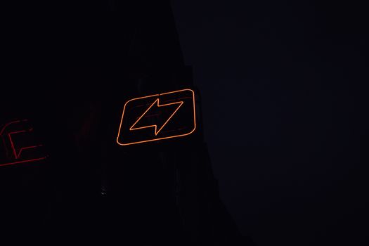 A glowing neon lightning bolt sign against a dark night background, symbolizing energy and electricity.