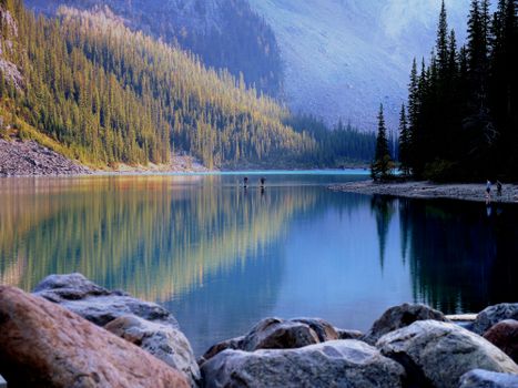 A tranquil mountain lake reflecting trees and sky, offering a scenic outdoor escape.