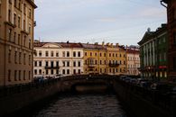 Granite embankment of canal between historical residential buildings and old bridge located in center of Saint Petersburg on cloudy day in Russia