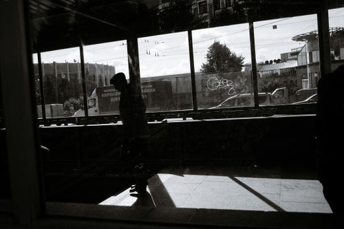 Free Black and white of anonymous man walking down in pedestrian underpass with glass walls in Russian city on sunny day Stock Photo