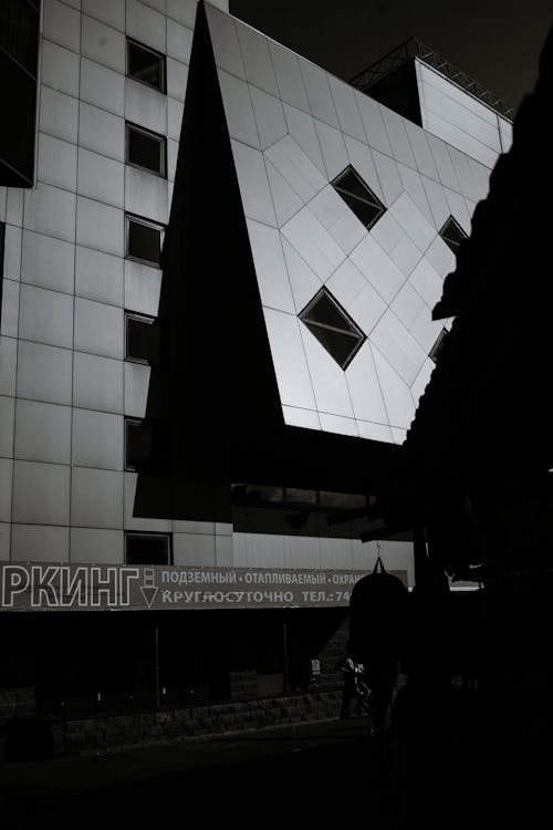 Black and white of geometric design exterior of contemporary shopping mall and signboard of parking in sunlight