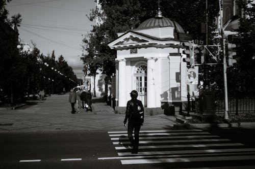 Unrecognizable pedestrian crossing road with zebra near classic chapel