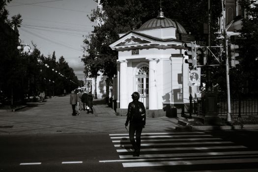Unrecognizable pedestrian crossing road with zebra near classic chapel