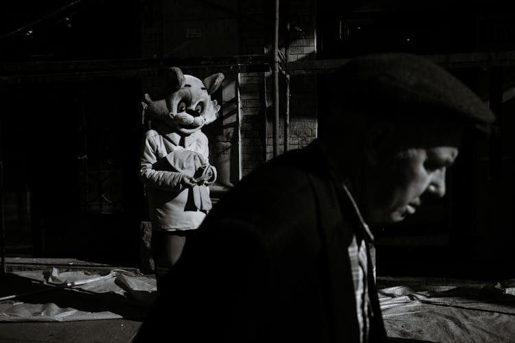 Senior Man In Hat Walking Near Actor Dressed Like Cat In City