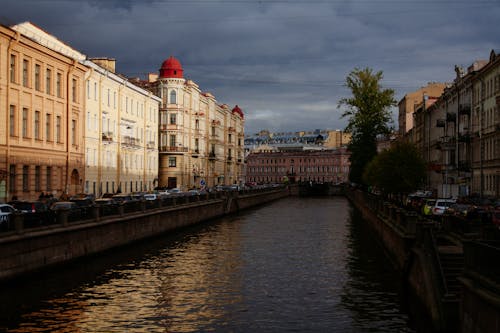 Picturesque scenery of famous historical canal surrounded by aged residential houses and parked cars located in Saint Petersburg Russian Federation before thunderstorm on summer day