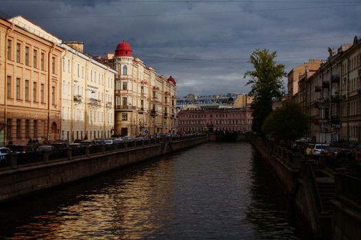 Picturesque scenery of famous historical canal surrounded by aged residential houses and parked cars located in Saint Petersburg Russian Federation before thunderstorm on summer day