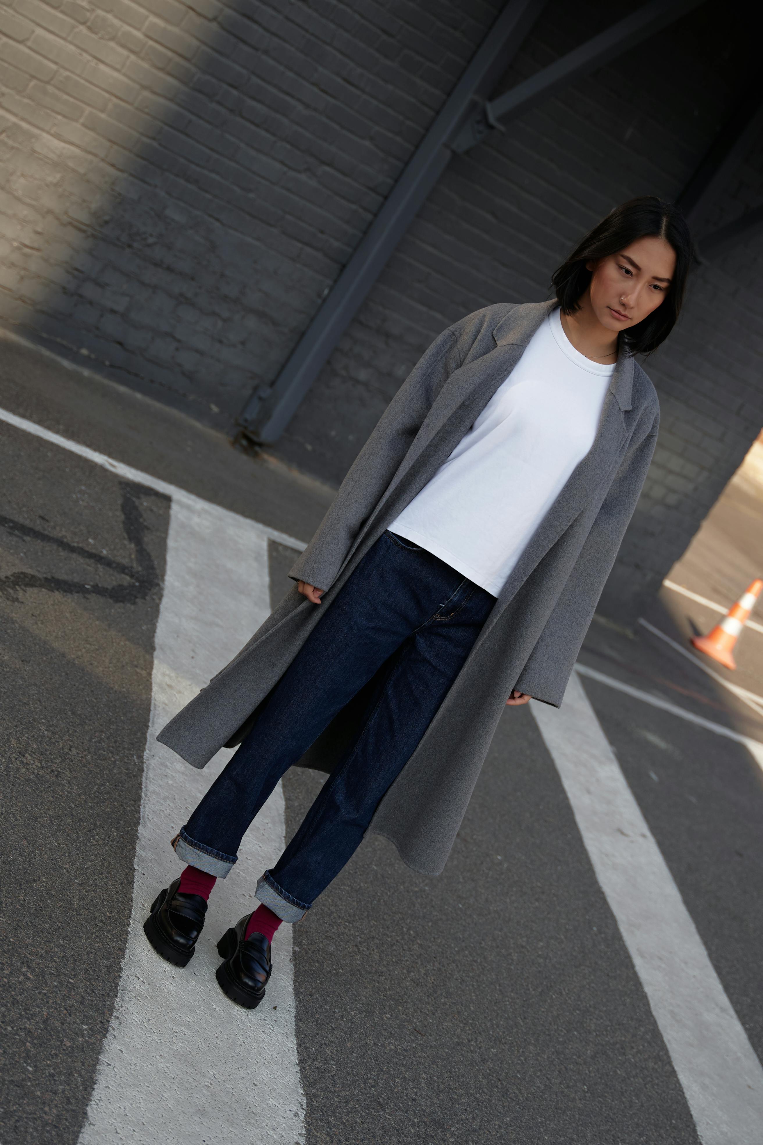 woman in white long sleeve shirt and black pants standing on gray asphalt road