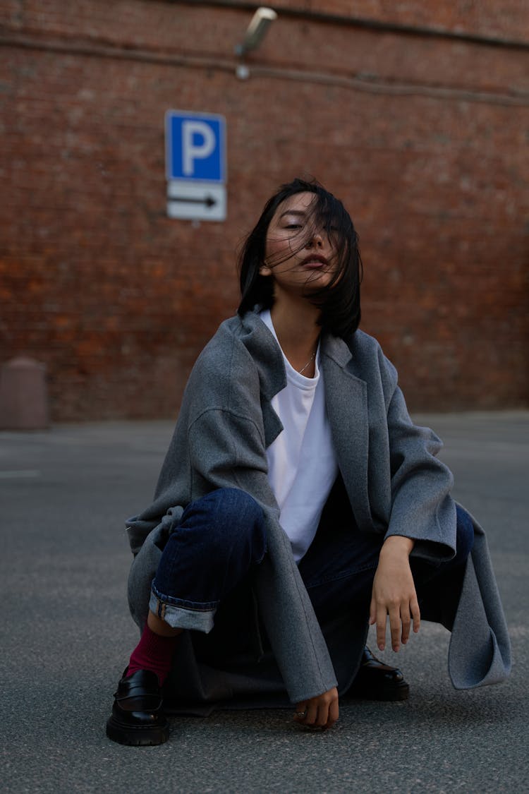 Woman Wearing A Gray Coat Squatting 