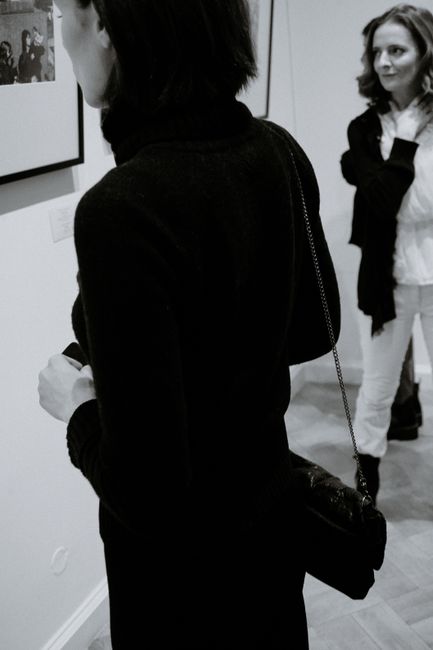 Black and white of crop anonymous young trendy female visitors watching photo in frame in museum