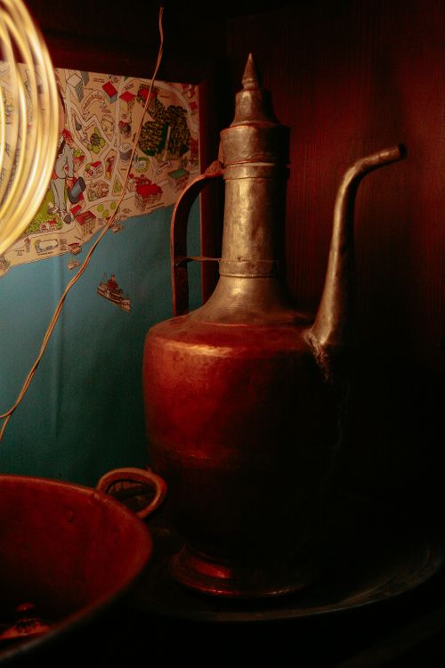 Free Aged jug with thin handle and nose near metal bowl and ornamental wall in house Stock Photo