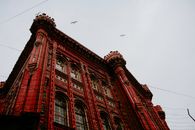 From below of aged masonry lyceum exterior with arched windows and ornamental walls under soaring birds in Istanbul