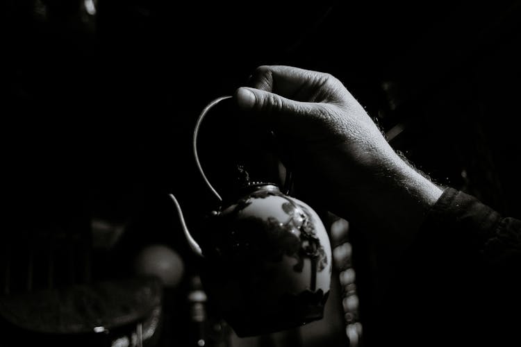 Crop Person Showing Ornamental Kettle At Home