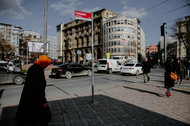 Unrecognizable People Walking On Pavement Near Road And Buildings