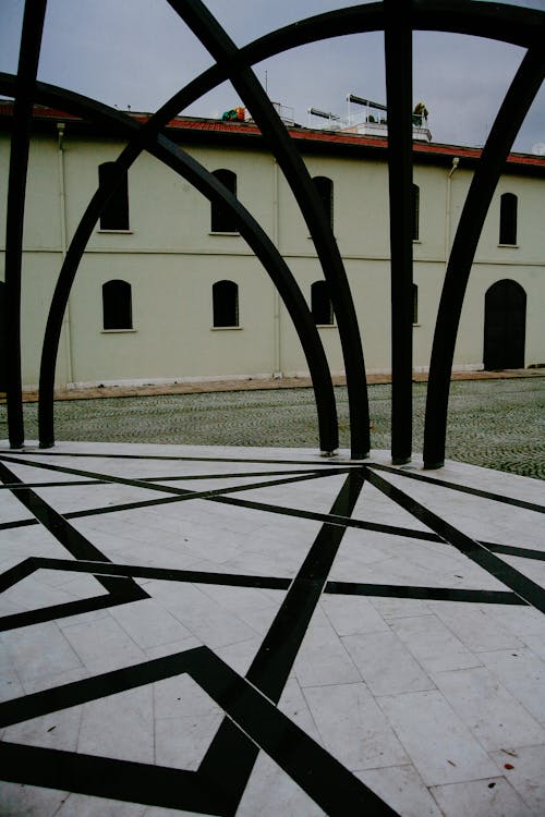 Metal arch against old building and lawn