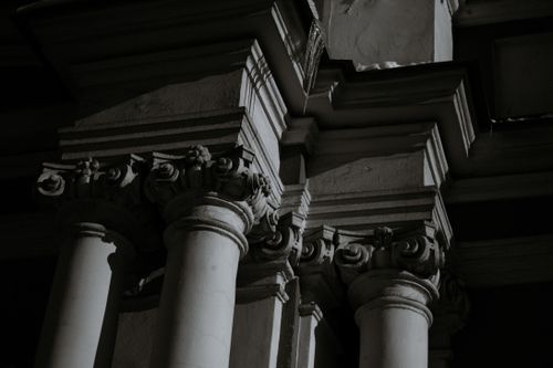 Free From below black and white of aged masonry building facade with ornament on column friezes in city Stock Photo