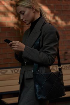 一位穿着时尚企业服装的金发年轻女子边走边看智能手机
