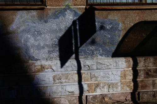Shadow of signboard on rough brick wall of urban building