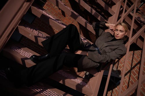 A Woman in Brown Blazer Sitting on Concrete Stairs