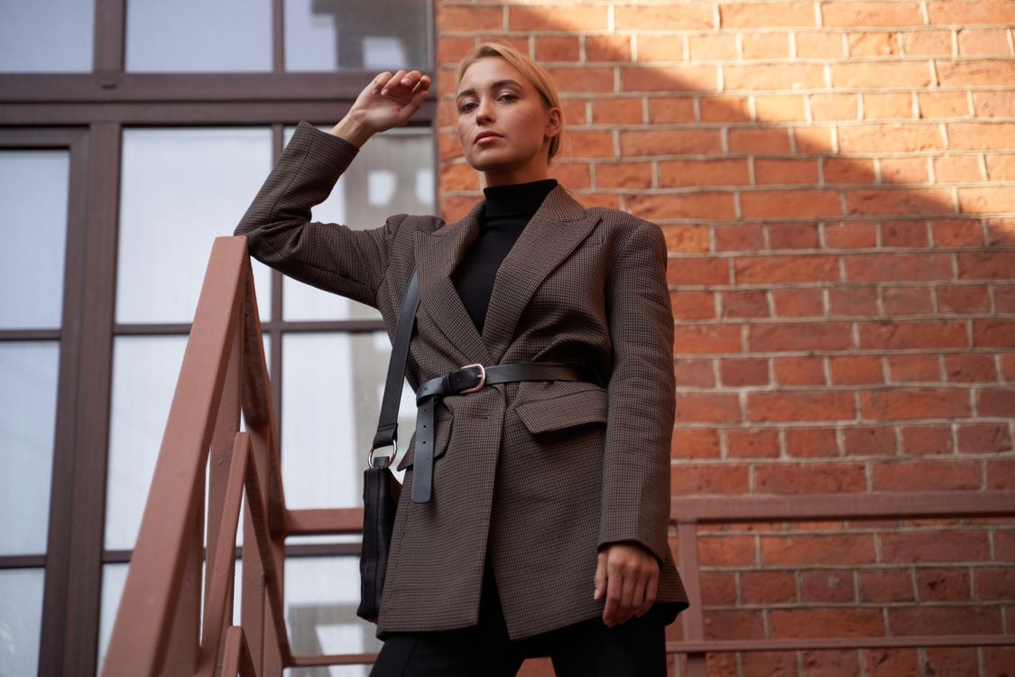 A Woman in Brown Blazer Standing Beside Brown Brick Wall · Free Stock Photo
