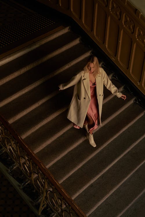 A Woman in Coat Walking Down the Stairs
