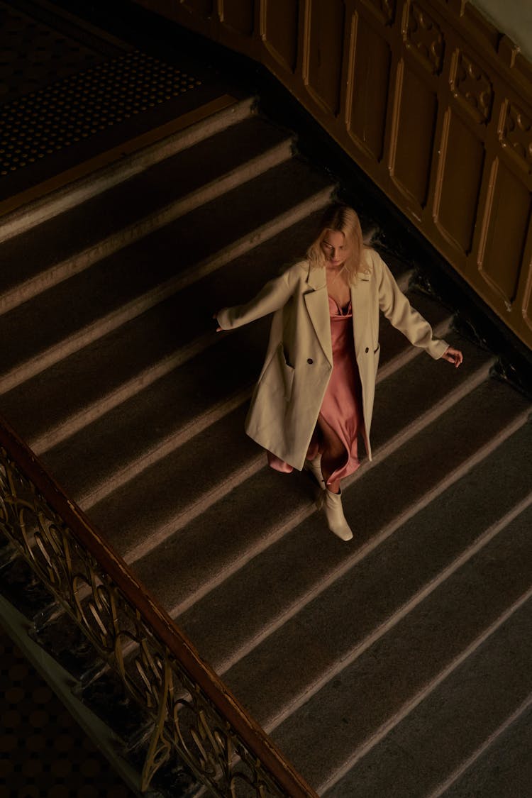 A Woman In Coat Walking Down The Stairs