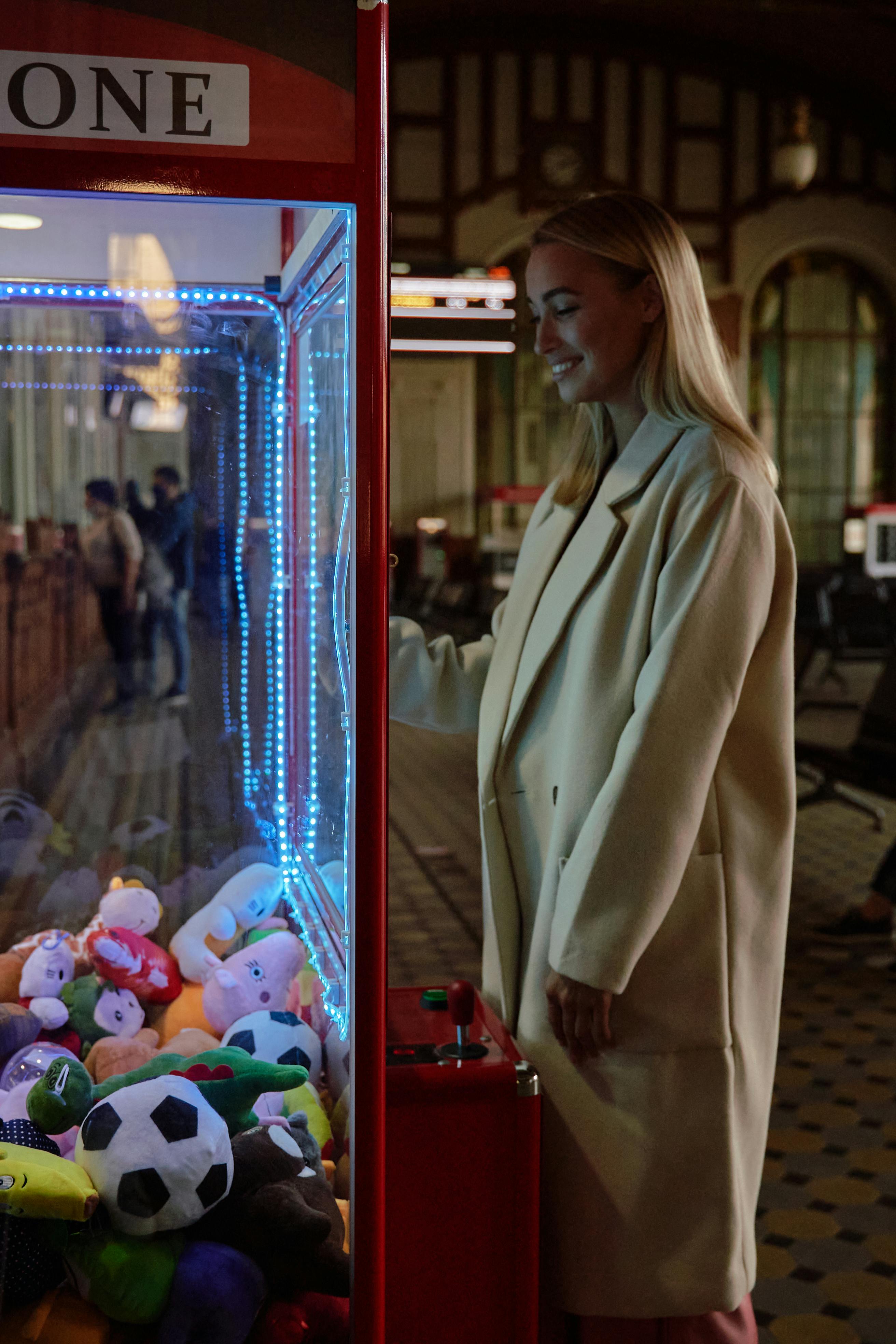 a woman in white coat standing beside the arcade game