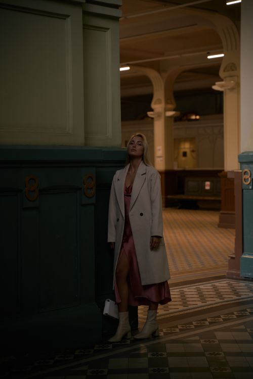 Free Elegant woman in a white coat and boots standing in a stylish indoor setting with vintage decor. Stock Photo