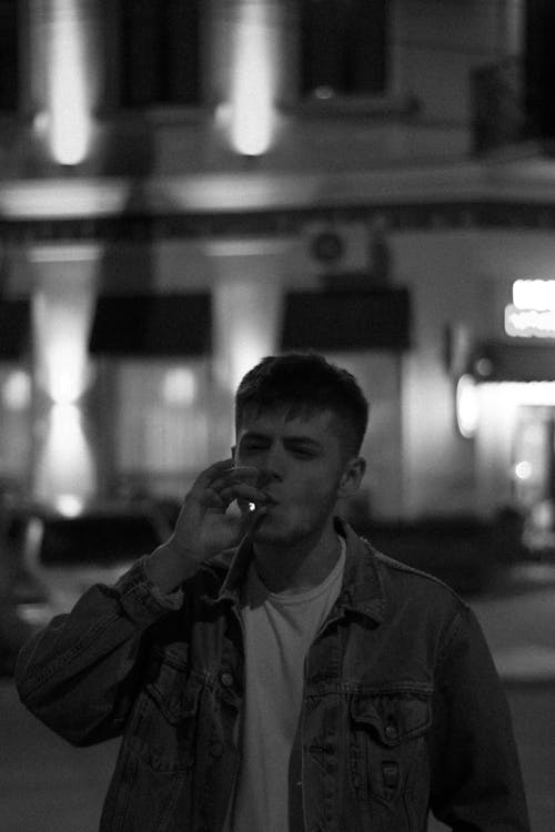 Grayscale Photo of a Man Smoking a Cigarette