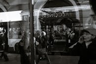 Black and white through glass wall view of anonymous passengers in trolleybus near sidewalk in town