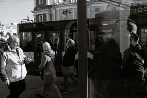 Free Black and white of unrecognizable people walking on pavement against trolleybus and old building in town in sunlight Stock Photo