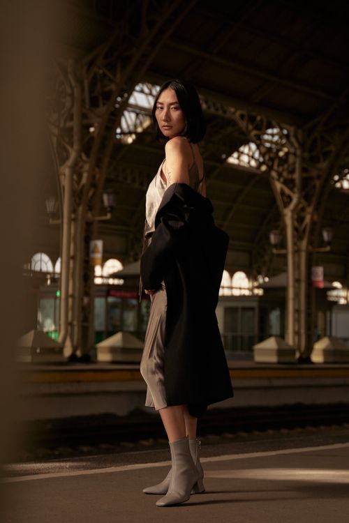 Free Woman in a chic outfit posing at a vintage train station, embracing a modern fashion vibe. Stock Photo