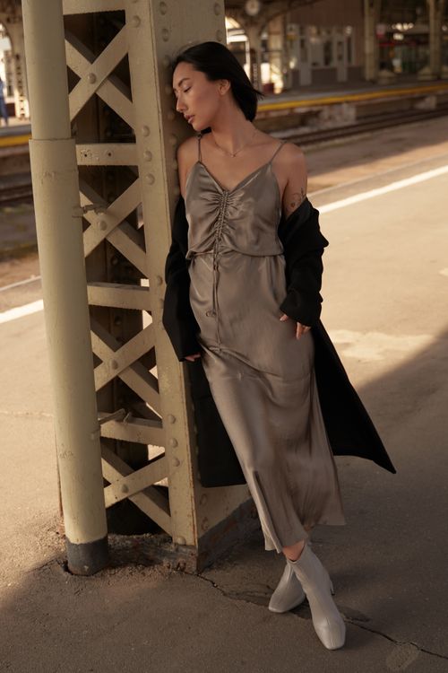 Free Fashionable Asian woman in a silk dress posing at a train station, exuding elegance and style. Stock Photo