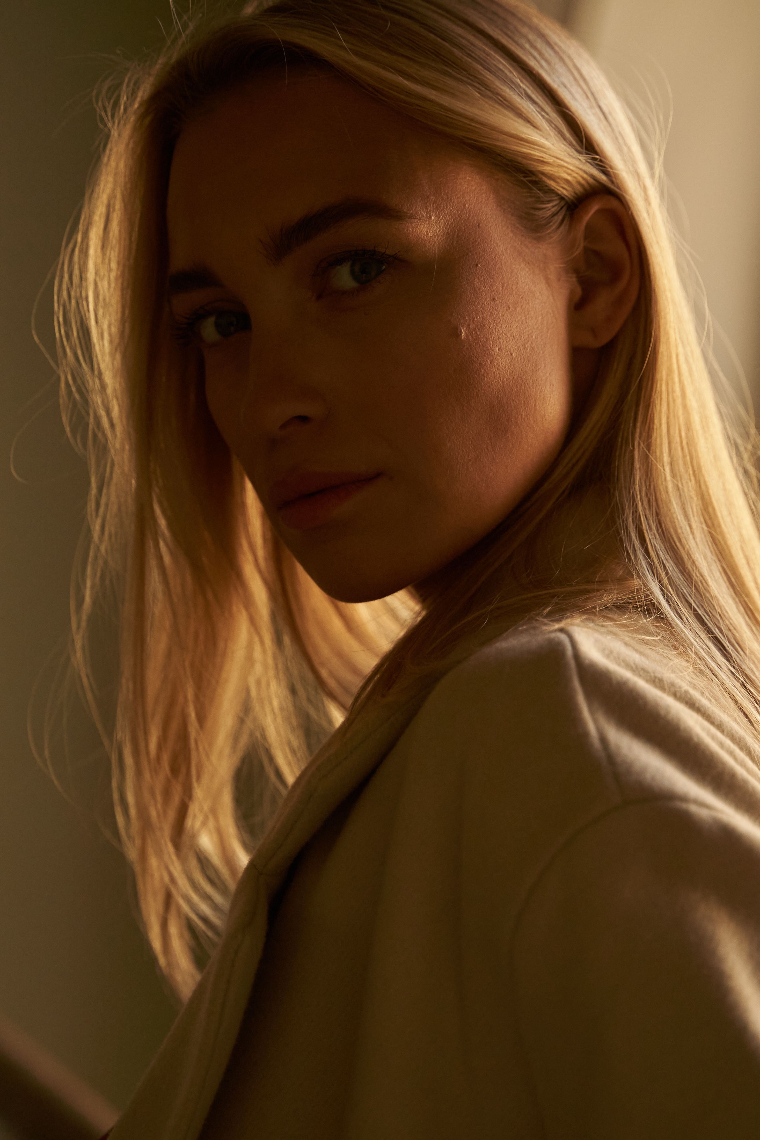 Elegant close-up portrait of a stylish blonde woman in warm lighting, showcasing beauty and fashion.