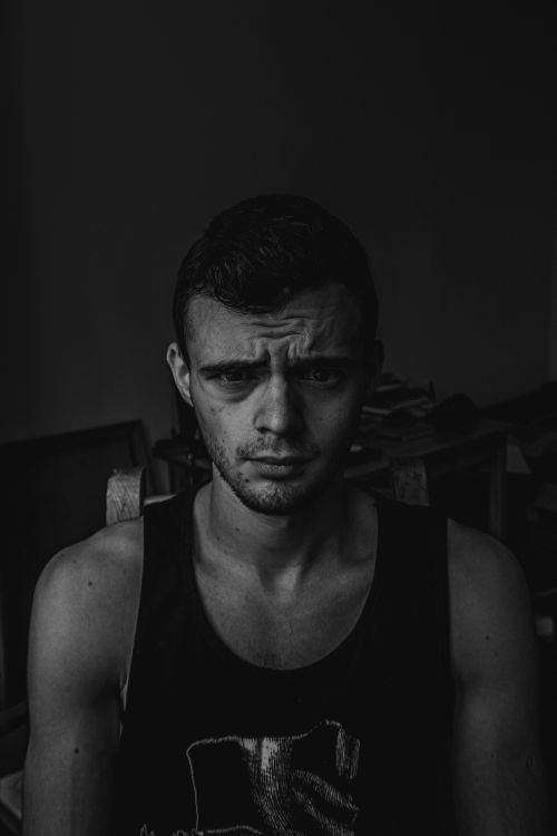 Free Striking black and white portrait of a young man with intense expression, captured indoors. Stock Photo