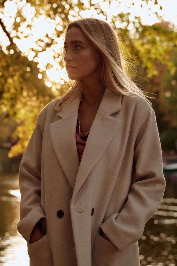 Woman in a camel faux fur coat with a cream knit