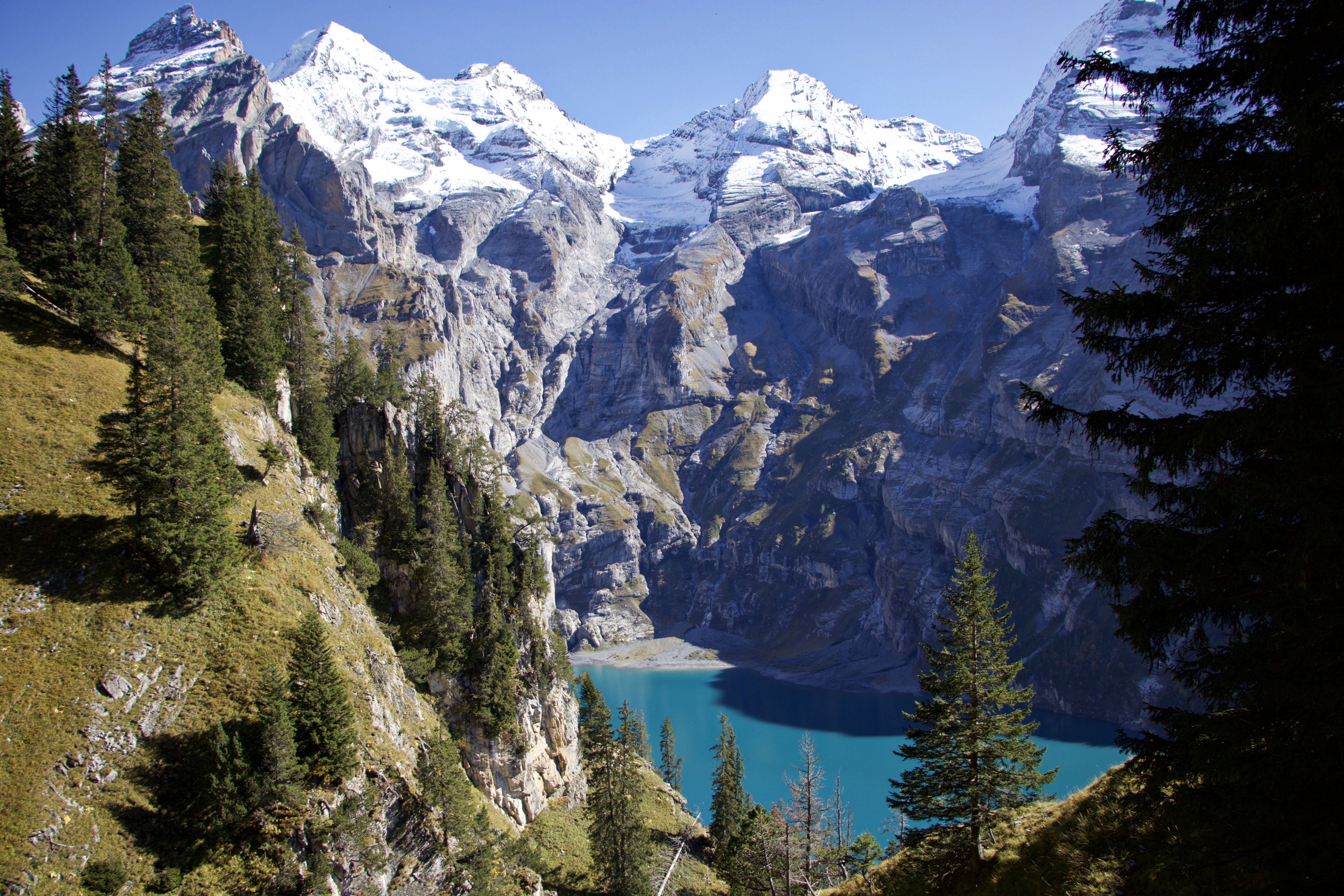 Breathtaking mountain lake surrounded by snow-capped peaks and lush pine forests. - Lago Oeschinen