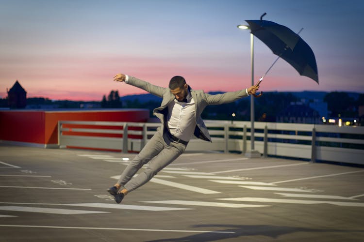 Man In Full Suit Jumping With Umbrella