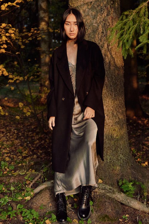 Woman in Black Trench Coat Leaning on Tree Trunk