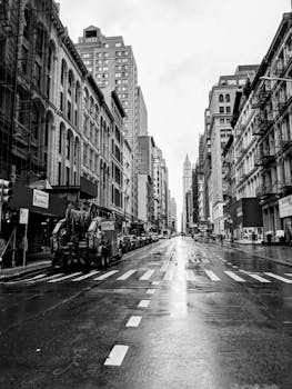 Black and white photo of a rainy day in New York City with wet streets.