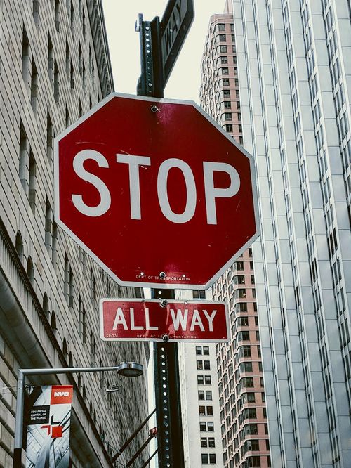 Free Close-up of a stop sign at an intersection in New York City with skyscrapers in the background. Stock Photo