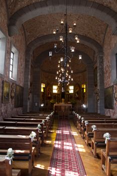 Beautifully decorated church interior featuring a chandelier and wooden benches leading to the altar.