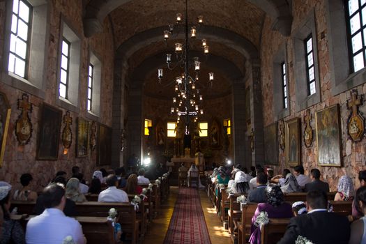 A wedding ceremony inside a rustic stone church with attendees and altar view.