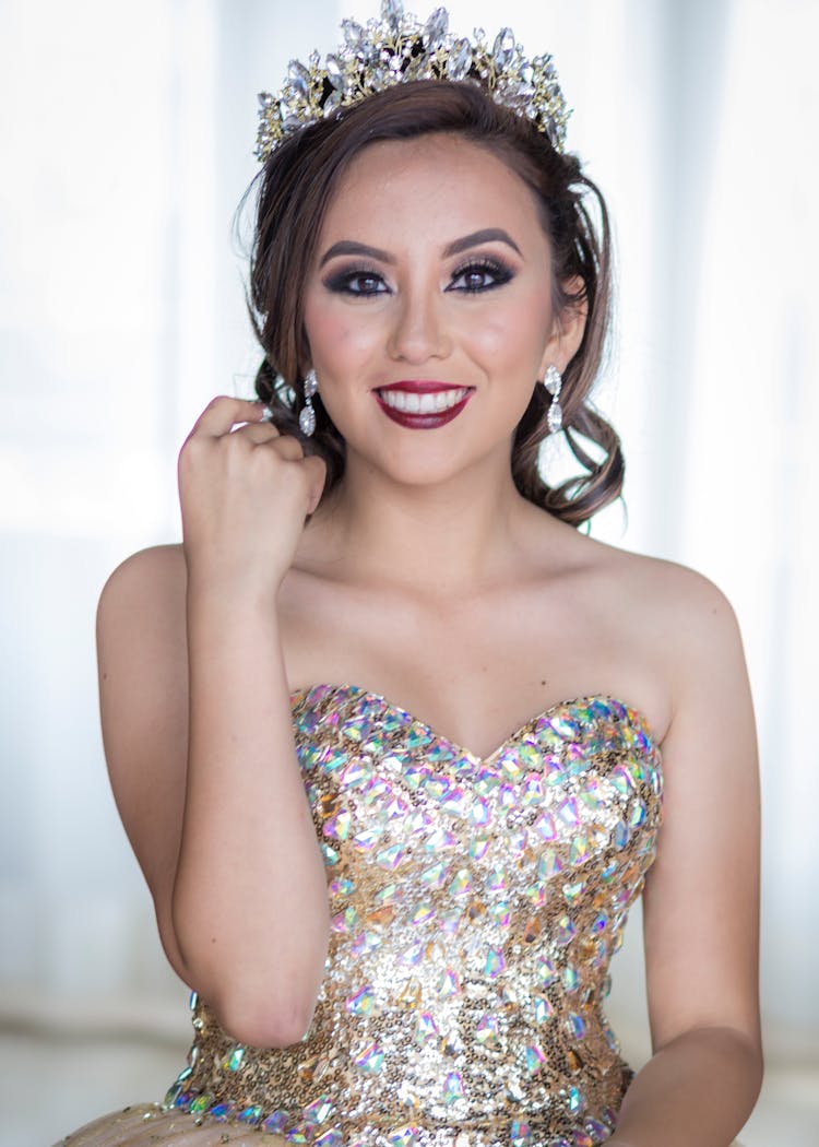 A Quinceanera Wearing Tiara And A Corset Gown With Rhinestones 