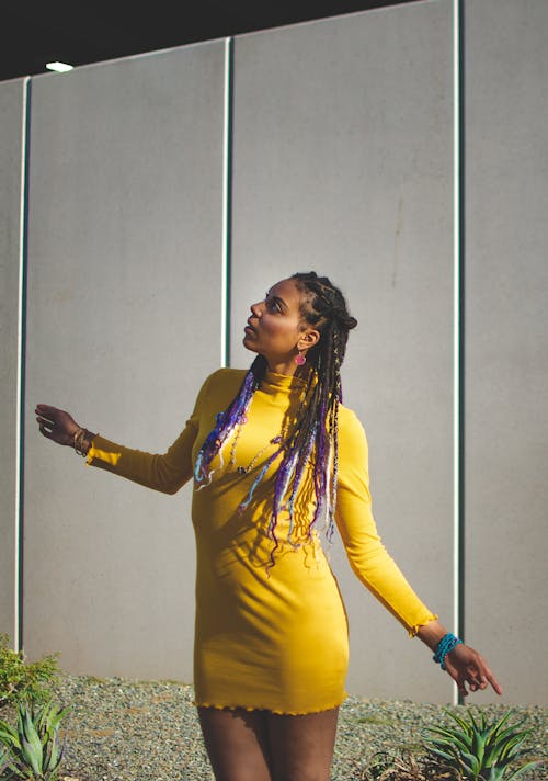 Black female standing near white wall in dress