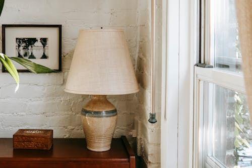 Interior design of light room corner with white brick walls with wooden cabinet and lamp placed near window