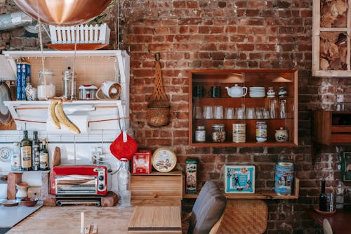 Vintage interior design with many cupboards filled with various dishware and decorations against shabby brick wall