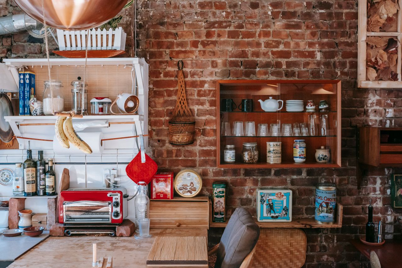 Warm country-style kitchen with brick walls, wooden shelves, and vintage kitchenware