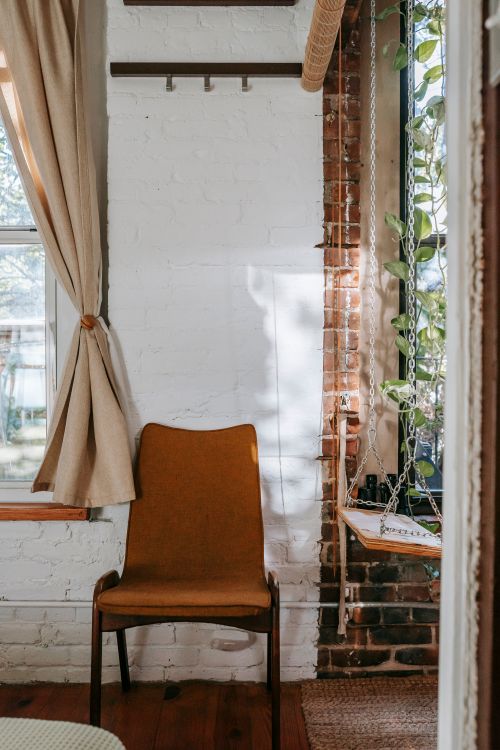 Free Light masonry living room furnished with comfy rustic chair and domestic indoors swings in daylight Stock Photo
