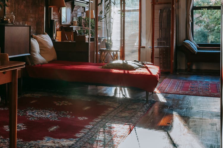 Cozy Bedroom With Vintage Furniture And Rugs On Parquet Floor In Sunlight