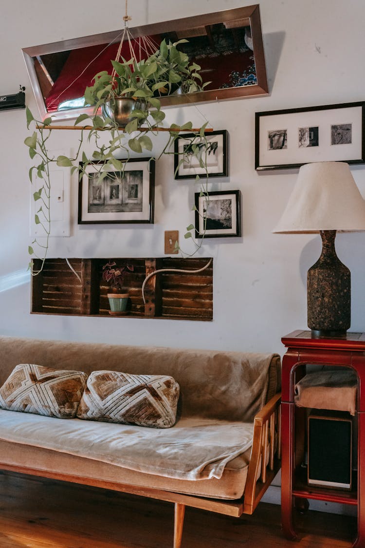 Couch And Small Display Cabinet With Elegant Lamp Near Wall Decorated With Framed Pictures At Home